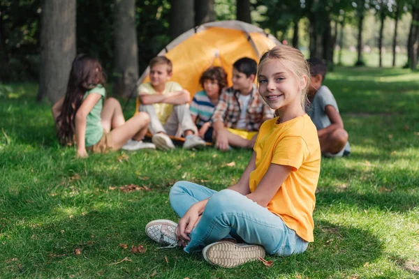 Selective focus of happy child smiling near multicultural friends in camp — Stock Photo