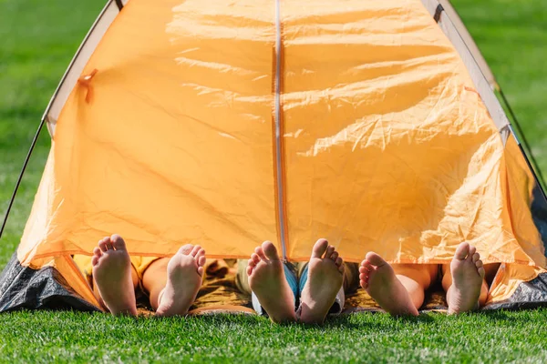 Vista recortada de los niños con los pies descalzos acostados en el campamento amarillo - foto de stock