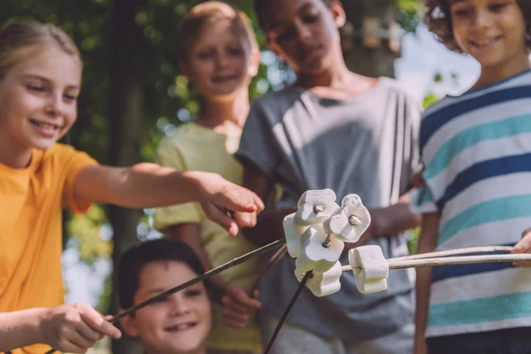 Foyer sélectif de l'enfant pointant du doigt les guimauves douces dans les bâtons près des garçons multiculturels — Photo de stock