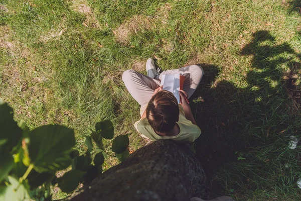 Top view of boy holding notebook while sitting on grass — Stock Photo