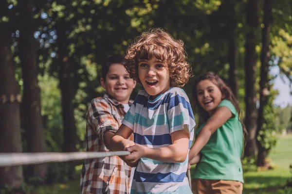 Selective focus of cheerful kids competing in tug of war — Stock Photo