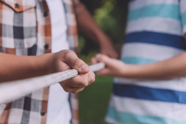 Cropped view of multicultural boys competing in tug of war — Stock Photo