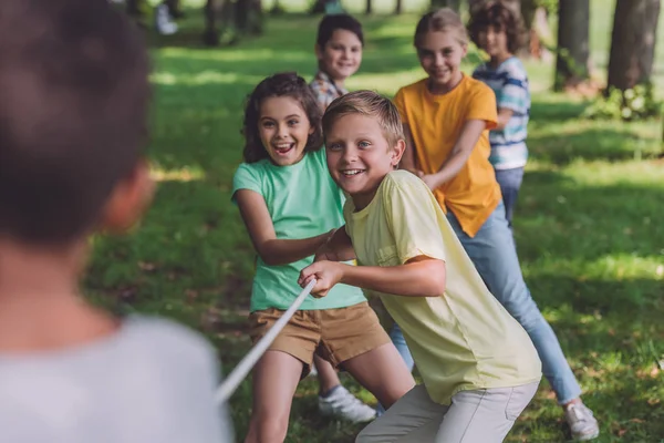 Selektiver Fokus fröhlicher Kinder im Tauziehen mit afrikanisch-amerikanischem Jungen — Stockfoto