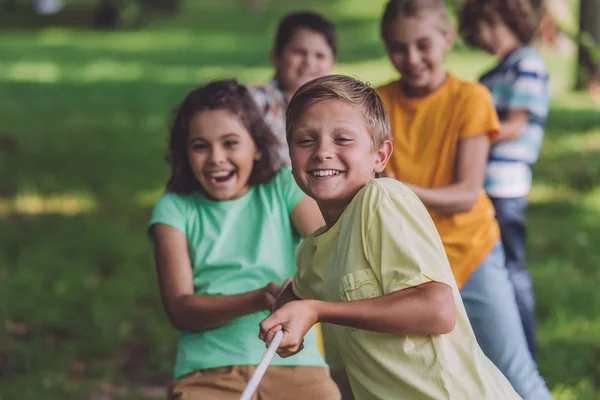 Selective focus of happy kids competing in tug of war — Stock Photo