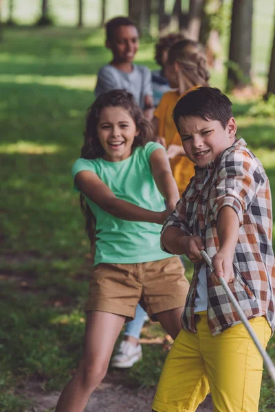 Selective focus of positive multicultural kids competing in tug of war — Stock Photo