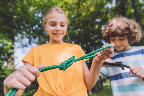 Selective focus of happy kids holding ropes in park — Stock Photo