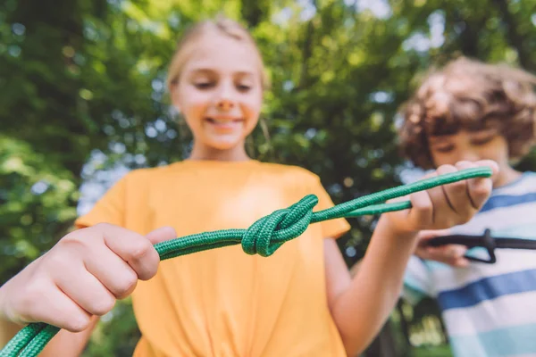 Foco seletivo de crianças sorridentes segurando cordas no parque — Fotografia de Stock