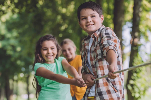 Enfoque selectivo de los niños positivos que compiten en tira y afloja - foto de stock