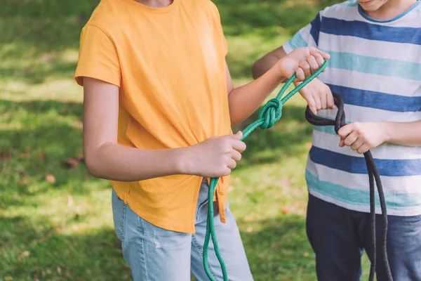 Cropped view of kids holding ropes with sea knots outside — Stock Photo