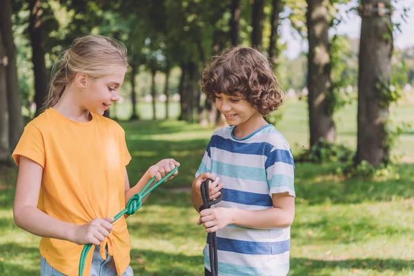 Glückliche Kinder, die draußen Seile mit Seeknoten halten — Stockfoto