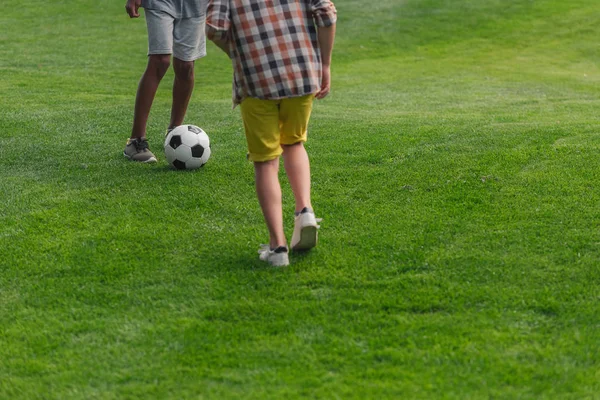 Vista recortada de chicos multiculturales jugando al fútbol - foto de stock