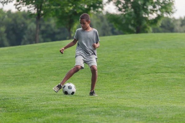 Bonito Africano americano menino jogando futebol na grama — Fotografia de Stock