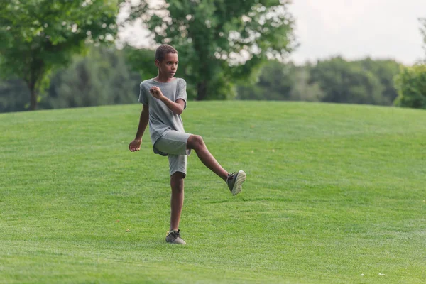 Bonito Africano americano menino exercitando na grama — Fotografia de Stock