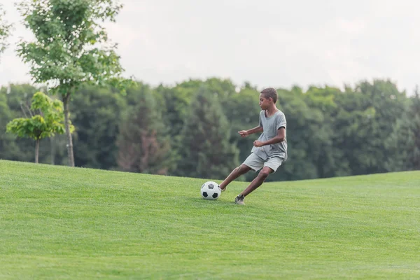 Carino ragazzo africano americano giocare a calcio su erba verde — Foto stock