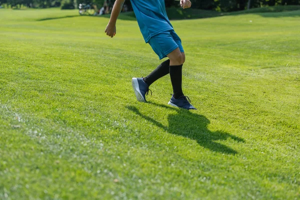 Cropped view of kid running on green grass — Stock Photo