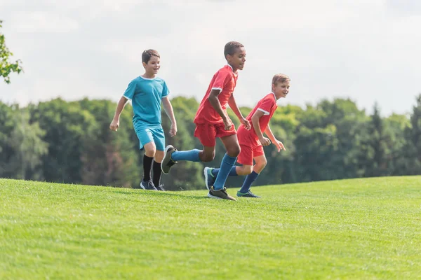 Happy multicultural boys running on grass — Stock Photo