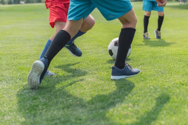 Обрізаний вид хлопчиків, які грають у футбол на траві — стокове фото
