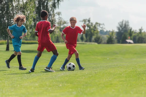 Foco seletivo de crianças multiculturais jogando futebol — Fotografia de Stock