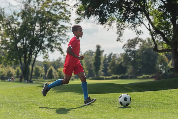 Carino africano americano bambino giocare a calcio su erba — Foto stock