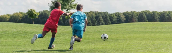 Panoramic shot of african american kid playing football with friend — Stock Photo