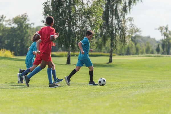 Abgeschnittene Ansicht von Kindern, die mit einem afrikanisch-amerikanischen Freund Fußball spielen — Stockfoto