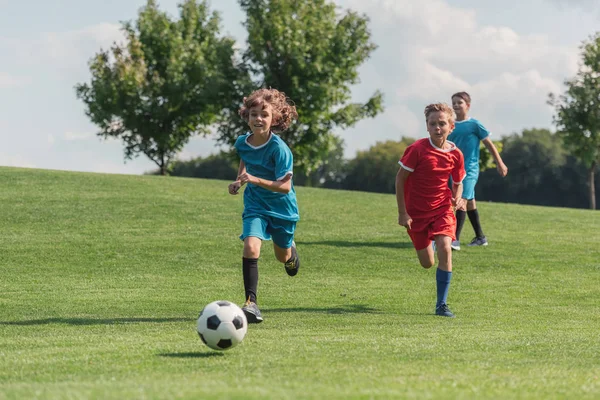 Happy kids running while playing football outside — Stock Photo