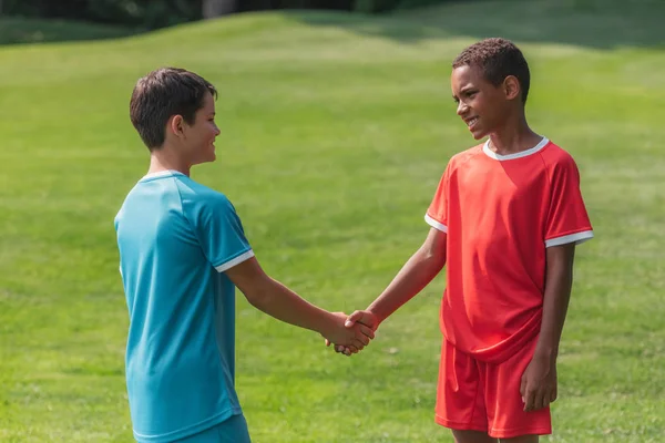 Happy multicultural kids shaking hands outside — Stock Photo