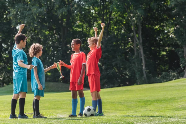 Enfoque selectivo de los niños multiculturales lindo gesto cerca del fútbol - foto de stock