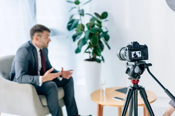 Selective focus of digital camera shooting businessman in office — Stock Photo