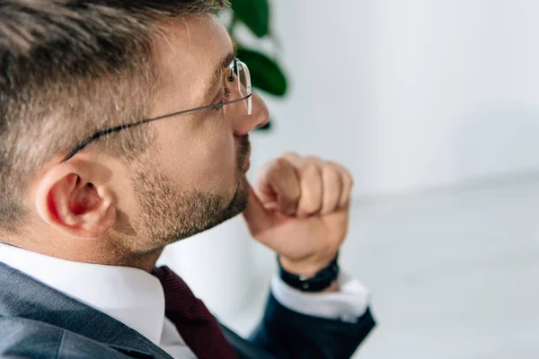 Ausgeschnittene Ansicht eines Geschäftsmannes in Anzug und Brille, der im Büro wegschaut — Stockfoto