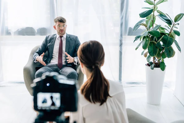 Foco seletivo de empresário bonito em terno e óculos conversando com jornalista — Fotografia de Stock