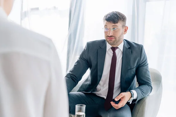 Enfoque selectivo de hombre de negocios guapo en traje y gafas hablando con el periodista - foto de stock