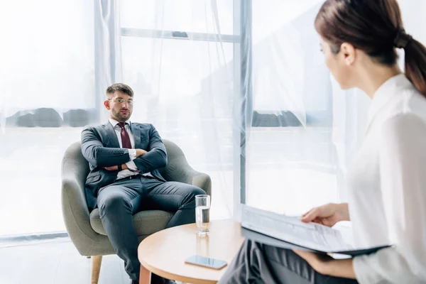 Enfoque selectivo de hombre de negocios guapo en traje y gafas hablando con el periodista - foto de stock