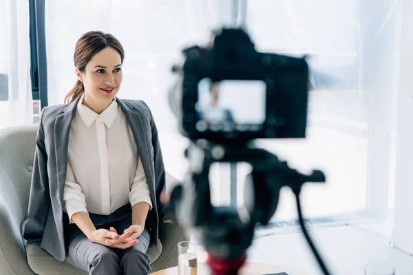 Focus selettivo di attraente giornalista in abbigliamento formale sorridente in ufficio — Foto stock