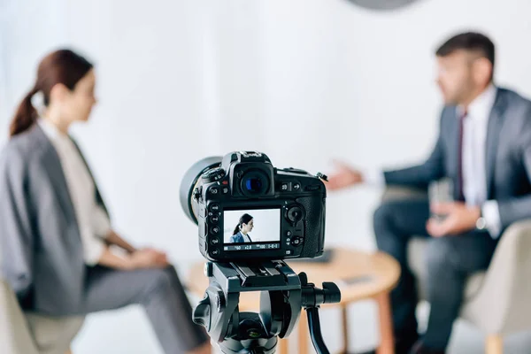 Selective focus of digital camera shooting journalist and businessman in formal wear — Stock Photo