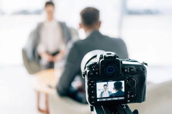 Selective focus of digital camera shooting journalist and businessman in formal wear — Stock Photo