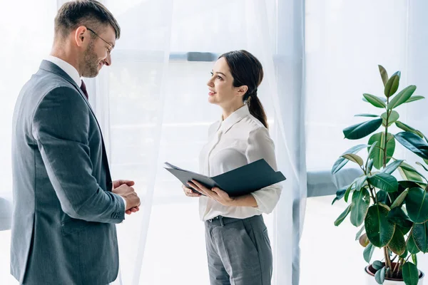 Vista lateral de periodista hablando con hombre de negocios en ropa formal - foto de stock