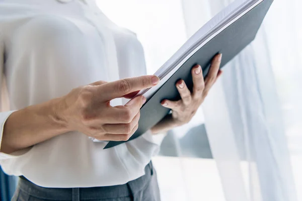 Cropped view of journalist in formal wear holding folder — Stock Photo