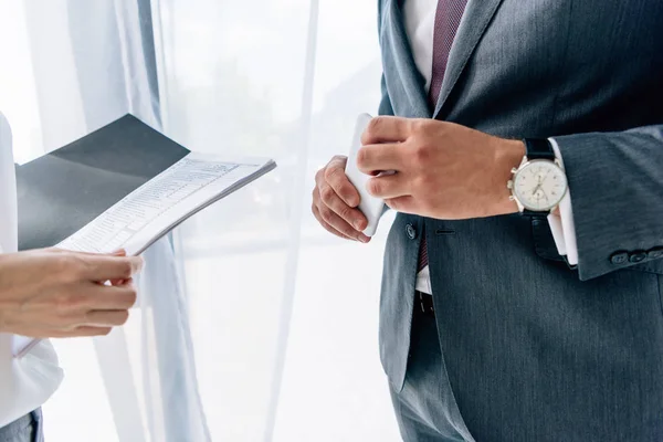 Cropped view of journalist holding folder and businessman with smartphone — Stock Photo