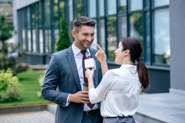 Журналист держит микрофон и разговаривает с бизнесменом в формальной одежде — стоковое фото