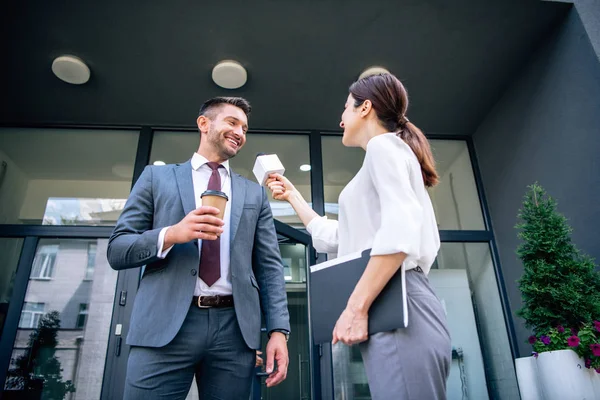 Journalist holding microphone and talking with businessman in formal wear — Stock Photo