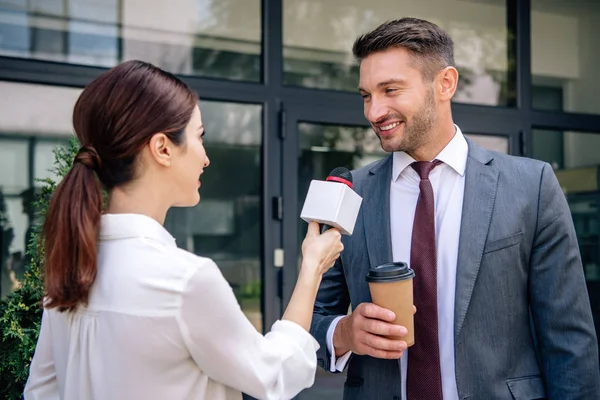 Jornalista segurando microfone e conversando com homem de negócios em vestuário formal — Fotografia de Stock