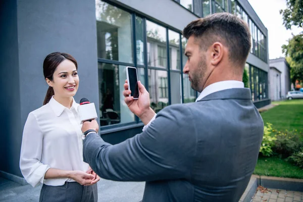 Journalist holding microphone and talking photo of businesswoman in formal wear — Stock Photo