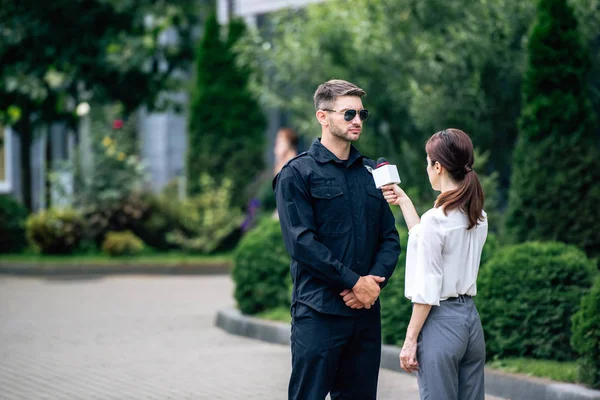 Журналист держит микрофон и разговаривает с красивым полицейским в форме — стоковое фото