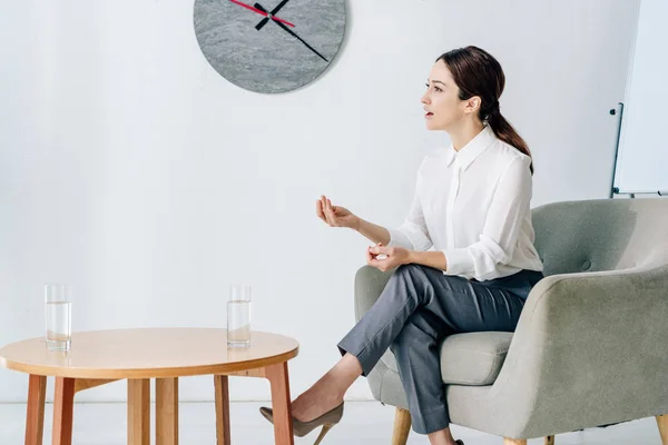 Attraktive Journalistin in offizieller Kleidung sitzt im Sessel im Büro — Stockfoto