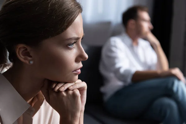 Upset pensive young woman and husband sitting on sofa — Stock Photo