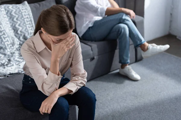 Partial view of upset couple sitting on sofa in living room — Stock Photo