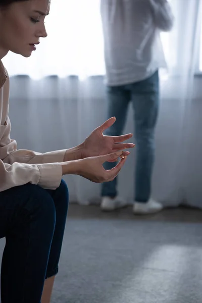 Vue recadrée de femme bouleversée décollant anneau et homme debout près de la fenêtre — Photo de stock