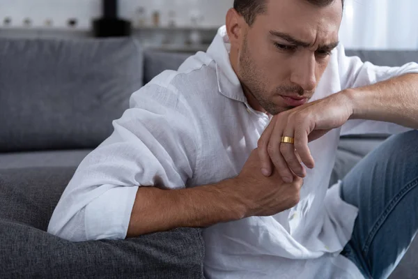 Depressed man in ring looking away in living room — Stock Photo