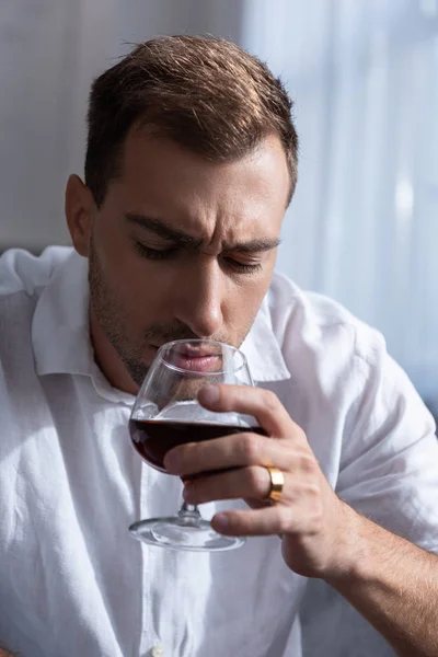 Uomo depresso in camicia bere cognac a casa — Foto stock